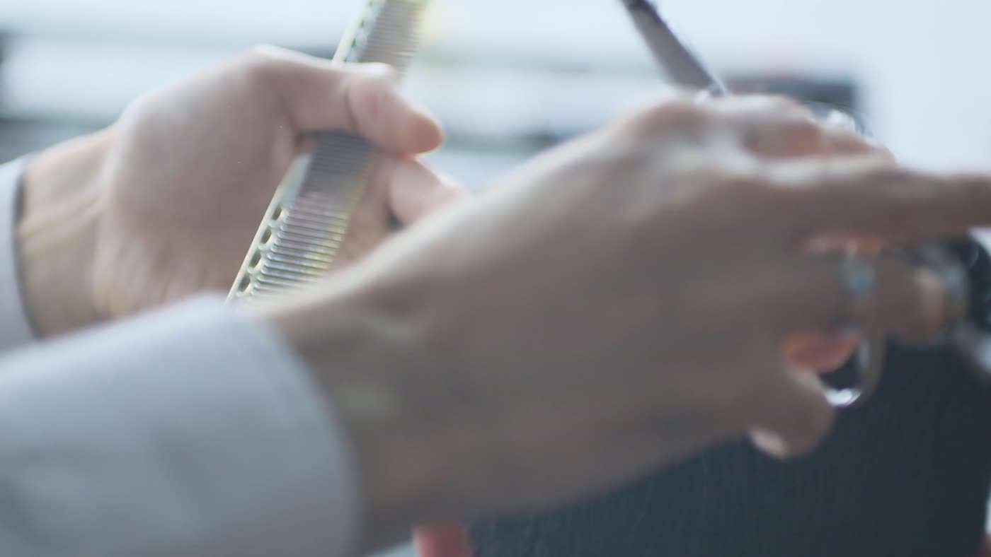 Cabelo escuro e volumoso de um cliente em um salão desfocado ao fundo